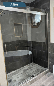 An after picture with standup shower. The tiles are large and gray.