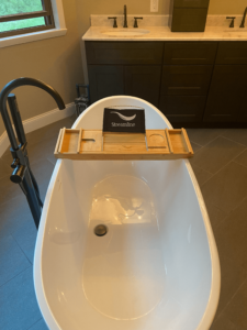 A large soaking tub with a small sign on a wood tray that says "Streamline."