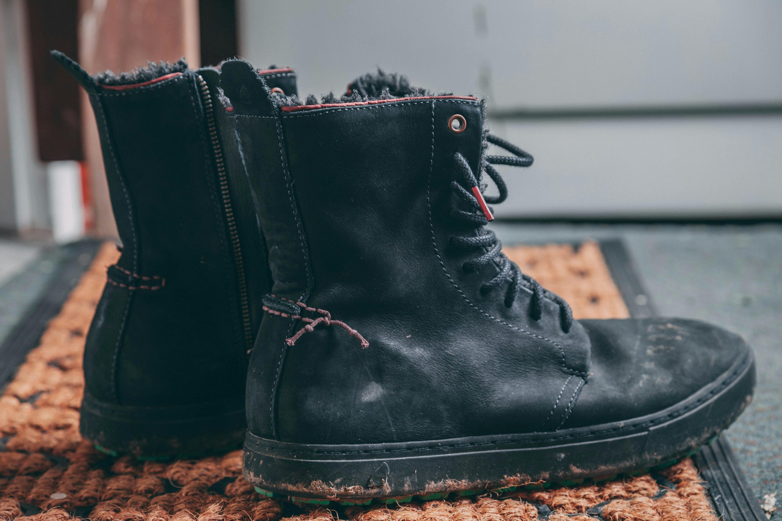 Dirty boots sit in an entryway on a doormat.
